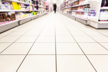 Abstract background blurred photograph of an aisle with shelves in bright modern drugstore at...