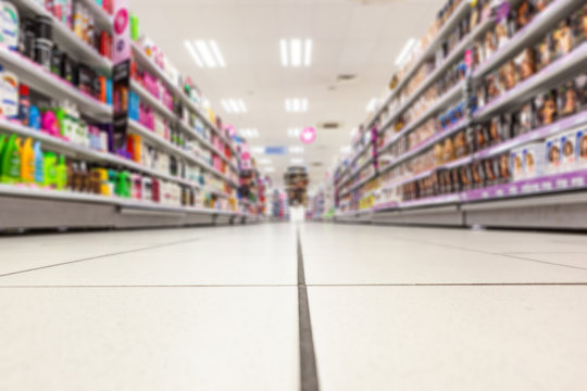 Abstract background blurred photograph of an aisle with shelves in bright modern drugstore at supermarket shopping center