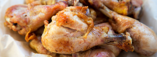 Fried chicken drumstick on baking sheet of paper, close-up.