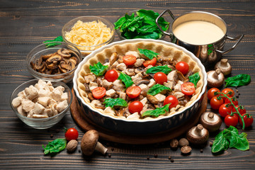 Traditional quiche tart in baking form with filling and ingredients