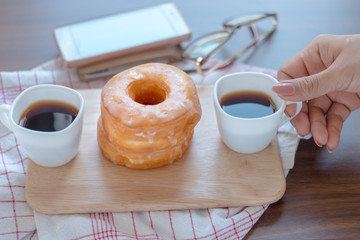 Woman pick cup of coffee on table by sugar donuts