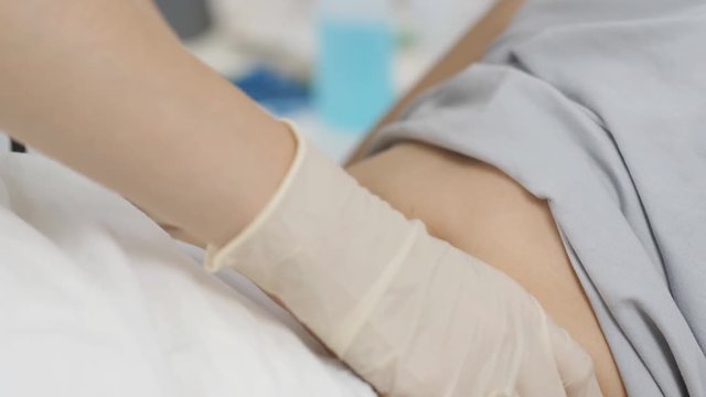 The doctor examines the abdomen of a patient lying in a hospital cravath.