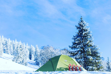 Tent winter mountains.Tent stands in the mountains in the snow. Snowshoes are beside the tent.