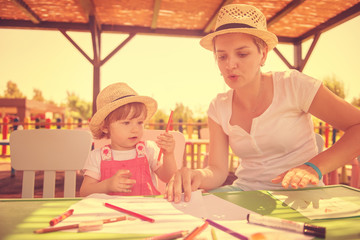 mom and little daughter drawing a colorful pictures