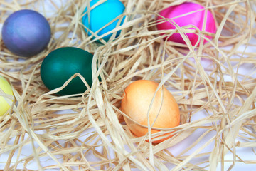 Fototapeta na wymiar Colorful easter eggs in raffia nest on white background