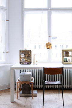 Moderner stylisher Arbeitsplatz mit Dekoration in Messing und Gold in Altbauwohnung vor Fenster