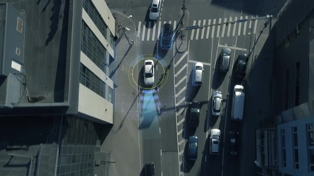 Top Down Aerial Drone: White Autonomous Self Driving Car Moving Through City. Concept: Artificial Intelligence Scans Surrounding Environment, Detecting Cars, Avoids Traffic Jams and Drives Safely.