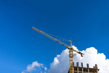Building construction site with tower crane against blue sky.