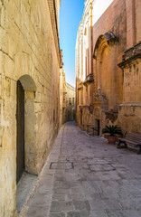Fototapeta na wymiar Mdina, Malta, old town narrow street with yellow stone buildings