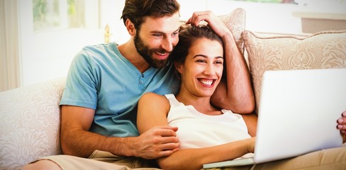 Couple sitting on sofa and using laptop