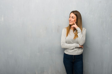 Young woman on textured wall thinking an idea while looking up
