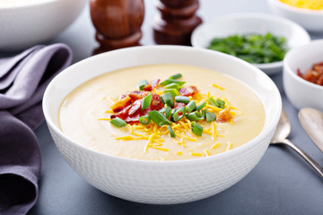 Potato cream soup with bacon, green onion and cheese close up