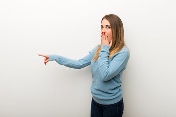 Blonde woman on isolated white background pointing finger to the side with a surprised face