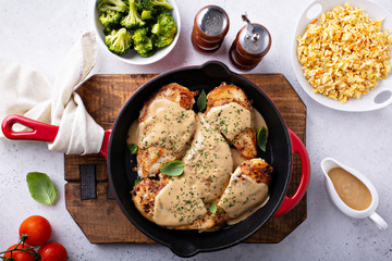 Cooked chicken breast seared in a cast iron skillet with creamy pan sauce - Powered by Adobe