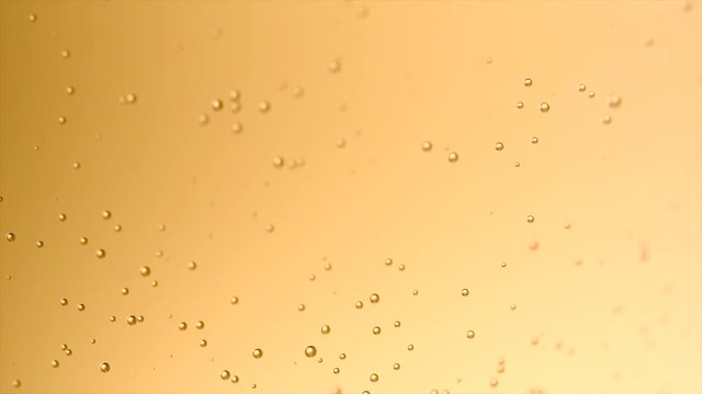 Champagne bubbles background closeup. Sparkling wine gold backdrop. Bubbly fizzing champagne closeup. Slow motion 4K UHD video footage. 3840X2160