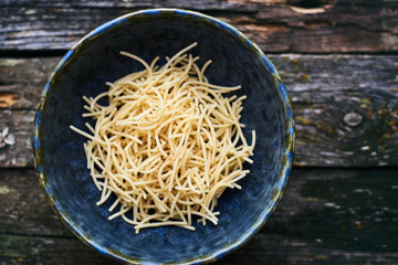Italian homemade raw noodles in a bowl on a wooden table top view