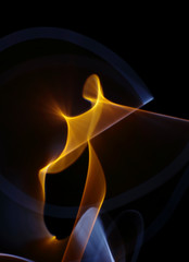 Fototapeta premium Orange-yellow-white curled line - ribbon painted by light on the black background. Improvisational painting by light.