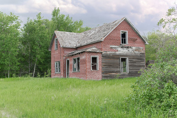 Fototapeta na wymiar old abandoned farm house surrounded by green trees