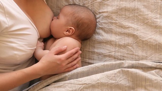 mother breastfeeding and hugging baby, close-up breast. Mom breast feeding her newborn child. Lactation infant. Baby eating milk before he sleeping. Mother feed her two month baby son with breast milk