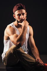 Fototapeta na wymiar Portrait of a bearded man a hip hop dancer or bboy sitting in urban style clothes and with inscription 