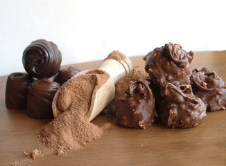 bunch of chocolate bonbon  and  cocoa powder in small  wooden spoon