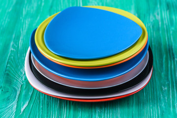 A stack of colored plates on a green wooden background.