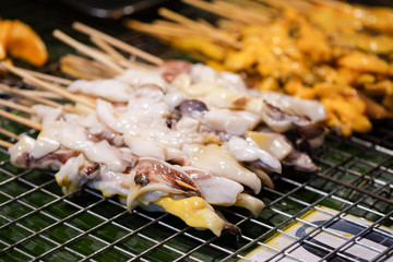 Fresh squid is placed on the grill to be sold in the market.