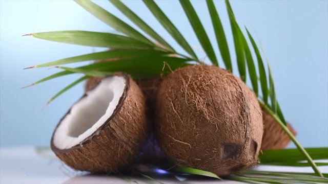 Coconut. Coconuts and green palm leaf rotated over yellow background. Healthy food, skincare concept. Rotation 4K UHD video 3840X2160