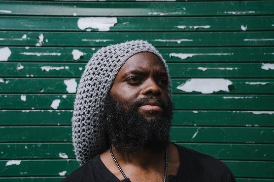 Thoughtful man standing against roller shutter 