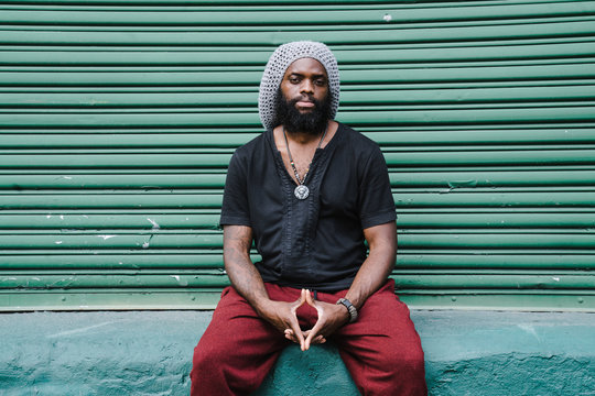 Portrait of man sitting against roller shutter
