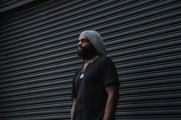 Thoughtful man standing against roller shutter