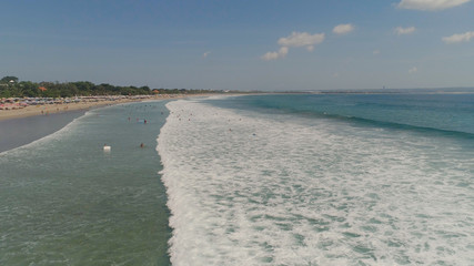 Obraz premium Aerial view sand beach with surfers and tourists, Kuta, Bali. surfers on water surface ocean catch wave. Seascape, beach, ocean, sky sea Travel concept