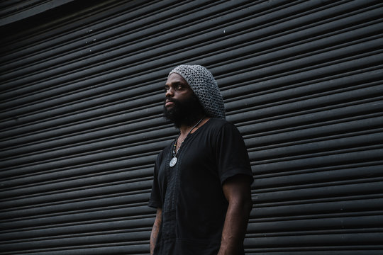 Thoughtful man standing against roller shutter