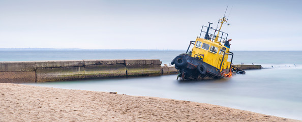 panorama to beach and pier with flooded tug boat 