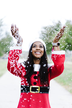 Smiling woman playing with confetti outdoors