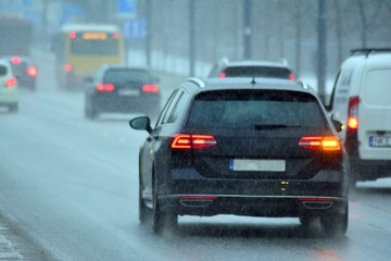 Fototapeta na wymiar Cars standing in row in traffic jam on city street on slippery snowy road in winter