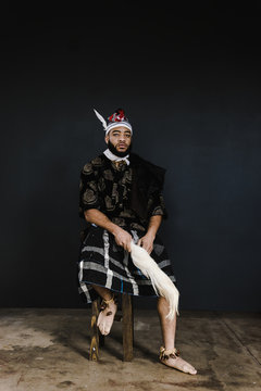 Portrait of man in traditional clothing sitting against black background