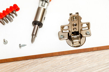 Furniture loop is installed and fixed on white facade with screwdriver.