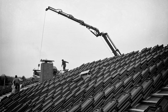 Dachziegel mit Dachdecker Hochkran in der Stadt auf die Baustelle transportieren, Dachdecken in Schwarz-Weiß Bild
