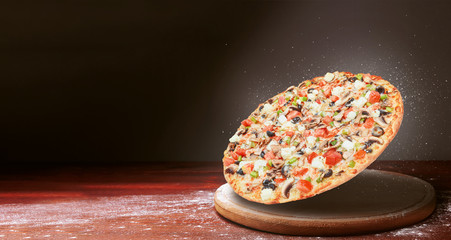 classic pizza on a dark wooden table background and a scattering of flour. pizza restaurant menu...