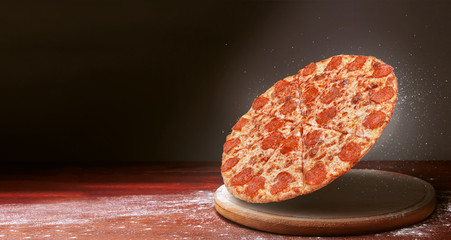 classic pizza on a dark wooden table background and a scattering of flour. pizza restaurant menu...