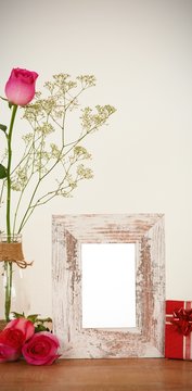 Rose flower in glass vase, photo frame and gift box