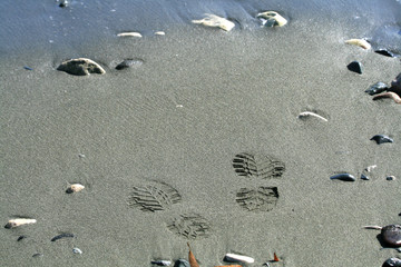 Close-up of two shoe prints and some pebbles on a sandy beach in Limassol, Cyprus