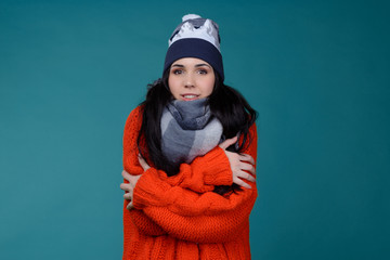 beautiful young smiling brunette woman in checkered gray wool winter hat and scarf. Portrait of beauty winter girl in knitted woolen clothing hat and Snood. Frozen in winter cold weather.