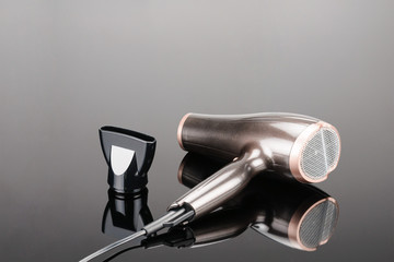 Brown hair dryer on the grey mirror background