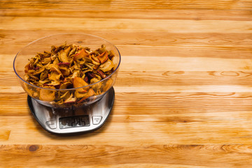 Dry apples in bowl on an electronic scale on a wood background with copy space