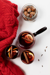Mulled wine in glasses with orange and spices near red sweater.