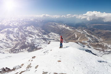 Climber stands at the top of Elbrus 5642m and looks at the mountains