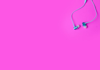 Headphones on color pink background, top view