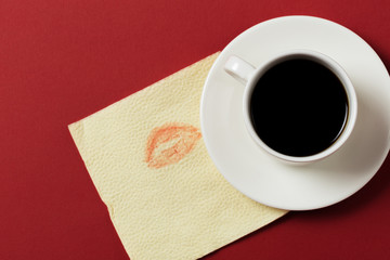 paper napkin with a kiss and coffee cup on red background.
